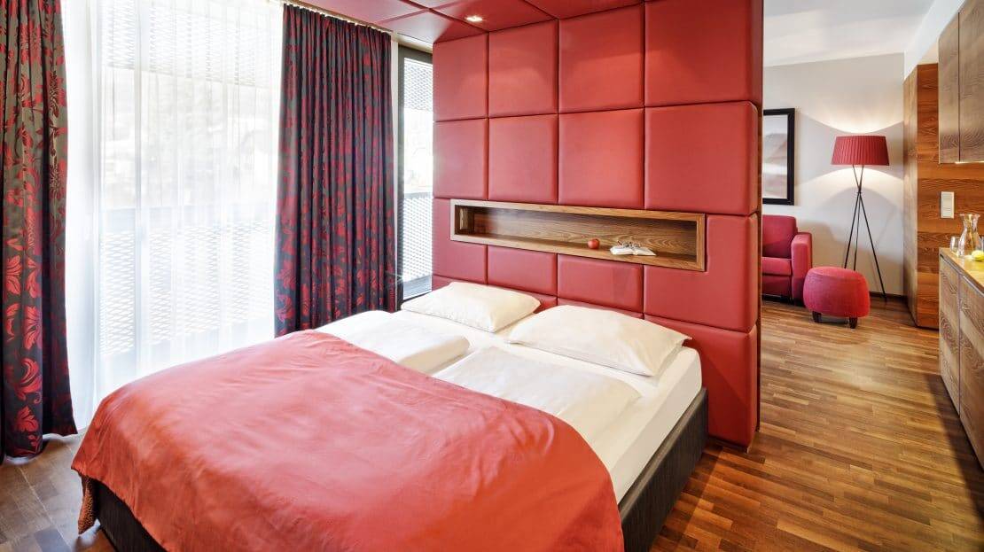 Asia Hotel & Spa, bezogenes Doppelbett vor einer hellroten Trennwand