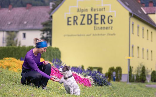 Erzberg Alpin Resort by Alps Resort, Frau mit Hund vor der Unterkunft mit Erzberg Alpin Aufschrift