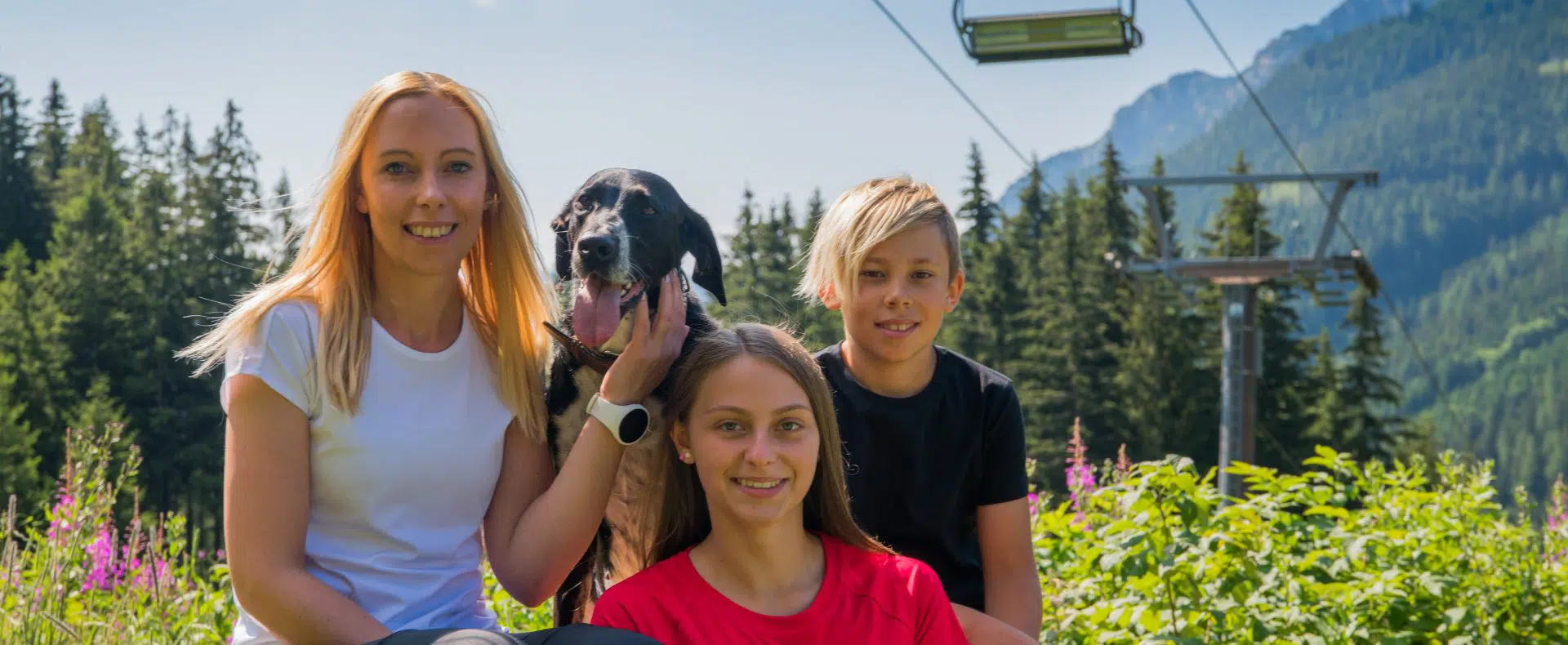 Familie mit Hund, im Hintergrund Berge und eine Gondel