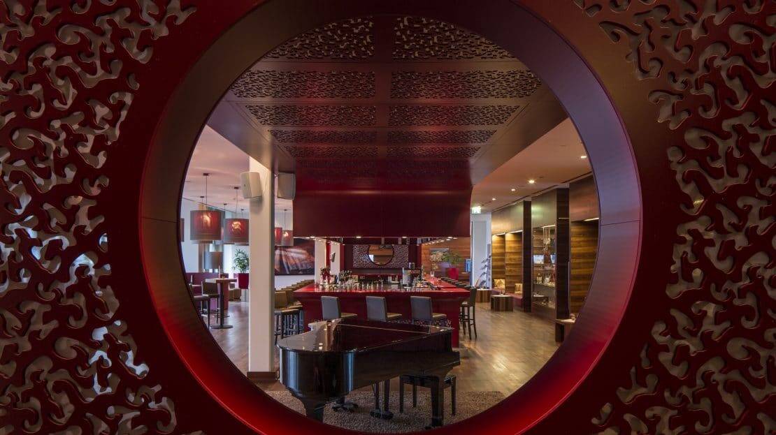 Asia Hotel & Spa Leoben, Piano im Saal fotografiert durch ein rundes Fenster