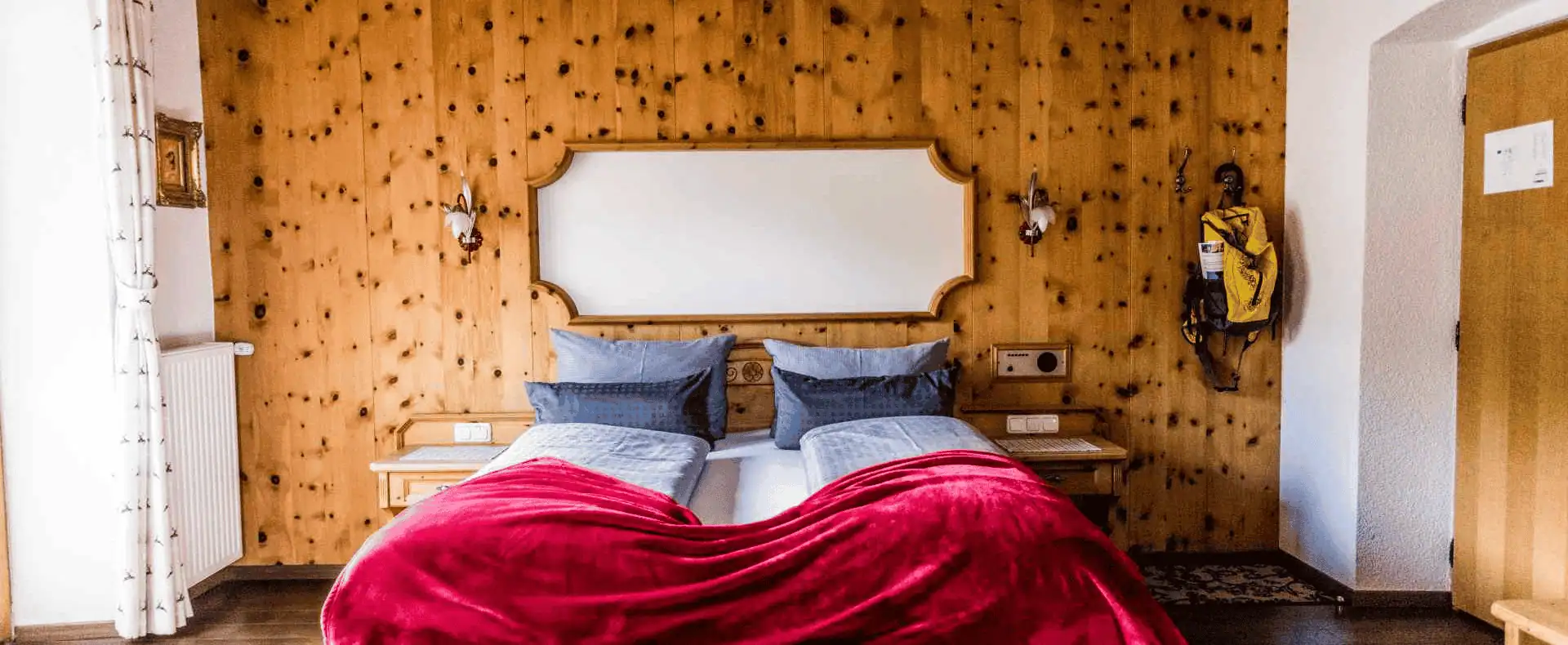 Doppelzimmer Alpenhotel Tyrol, Bett mit roter Überdecke