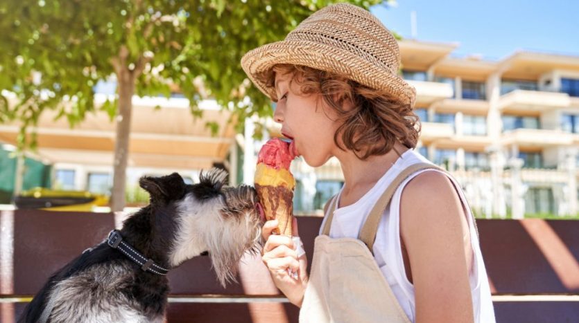 Kind isst mit Hund gemeinsam ein Eis