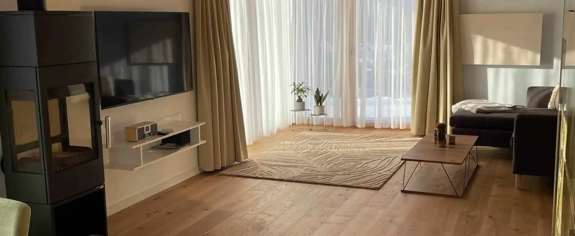 Wohnbereich mit Fernseher, Sofa und Balkontür