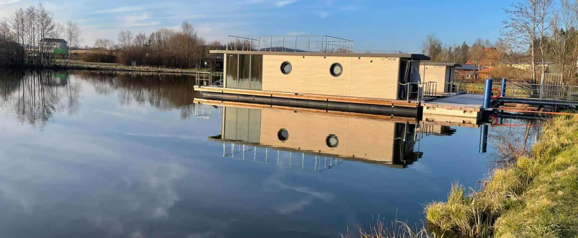 Waidlerland Feriendorf, Hausboot im Wasser. Urlaub mit Hund im Bayrischen Wald ist im Waidlerland auch auf einem einzigartigen Hausboot möglich. /Foto: Waidlerland Feriendorf
