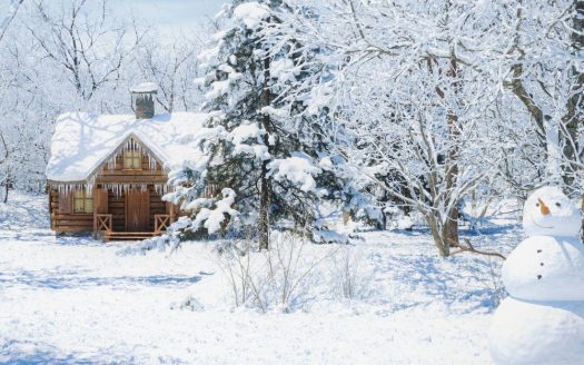 Eine idyllische Winterszene mit einer kleinen Holzhütte, umgeben von schneebedeckten Bäumen. Im Vordergrund steht ein fröhlich aussehender Schneemann, der zur freundlichen, einladenden Stimmung beiträgt. Die Szene ist von einem klaren, blauen Himmel überzogen und suggeriert einen ruhigen, sonnigen Wintertag.