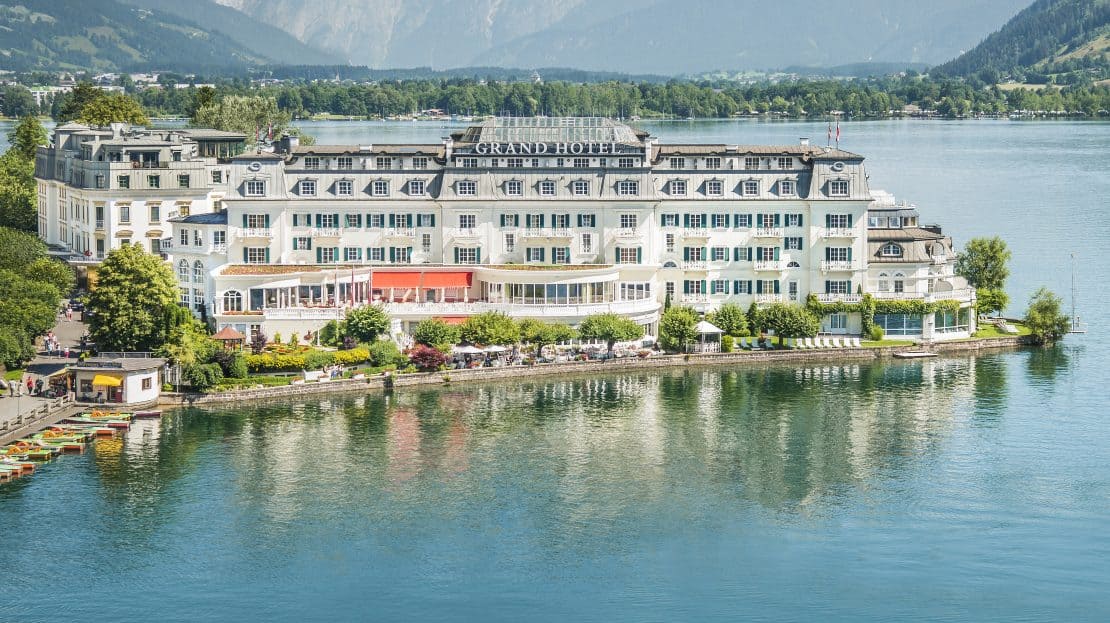 Luftaufnahme vom Grand Hotel in Zell am See mit dem Tourismusschiff Schmittenhöhe im Vordergrund. Im Hintergrund das Steinerne Meer.