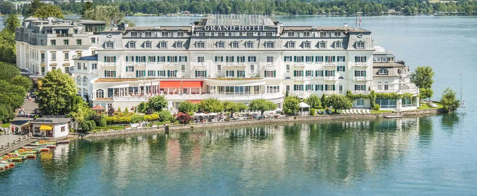 Luftaufnahme vom Grand Hotel in Zell am See mit dem Tourismusschiff Schmittenhöhe im Vordergrund. Im Hintergrund das Steinerne Meer.