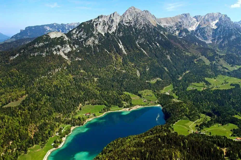 Ein smaragdgrüner Bergsee, eingebettet in eine idyllische Waldlandschaft, umgeben von den imposanten Gipfeln der Kitzbüheler Alpen.
