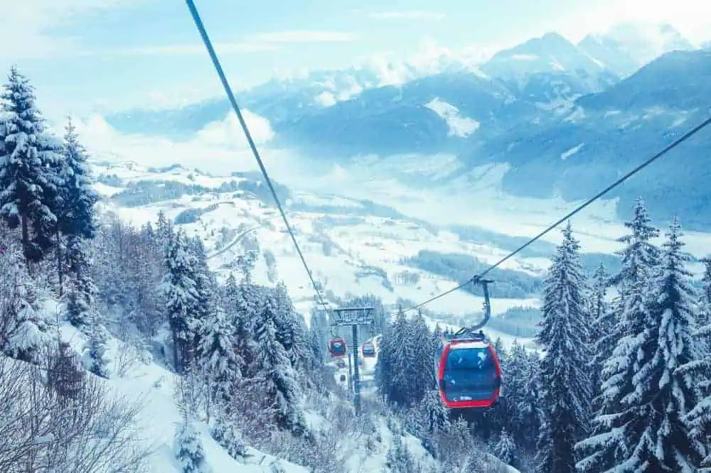 Eine winterliche Gondelfahrt über schneebedeckte Wälder und Berge in den Kitzbüheler Alpen. Der Blick reicht weit über die tief verschneite Landschaft.