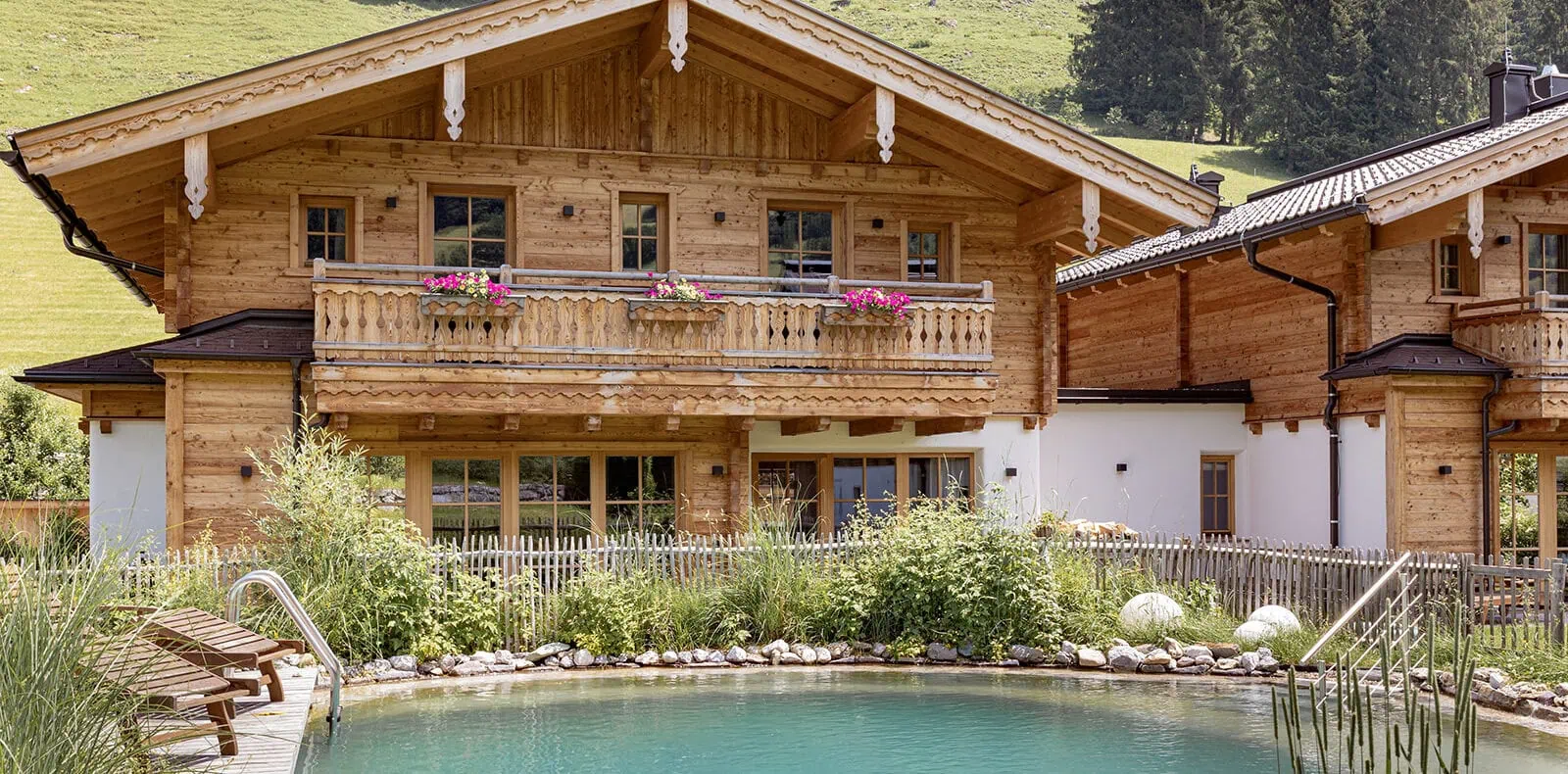 Naturbadeteich vor den Birnbaum Chalets mit Blick auf die Alpen und Holzchalets