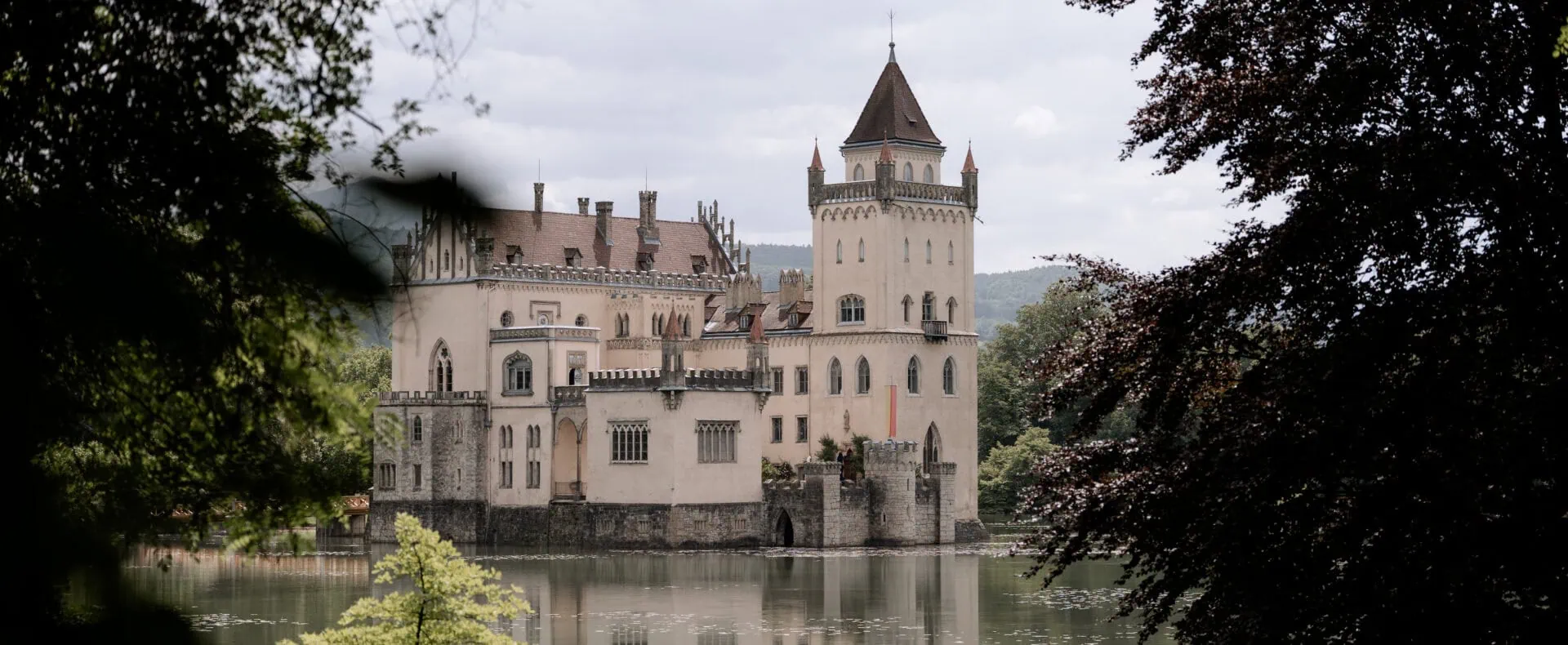 Blick auf Schloss Anif am See, umgeben von Bäumen und ruhiger Natur nahe Salzburg.