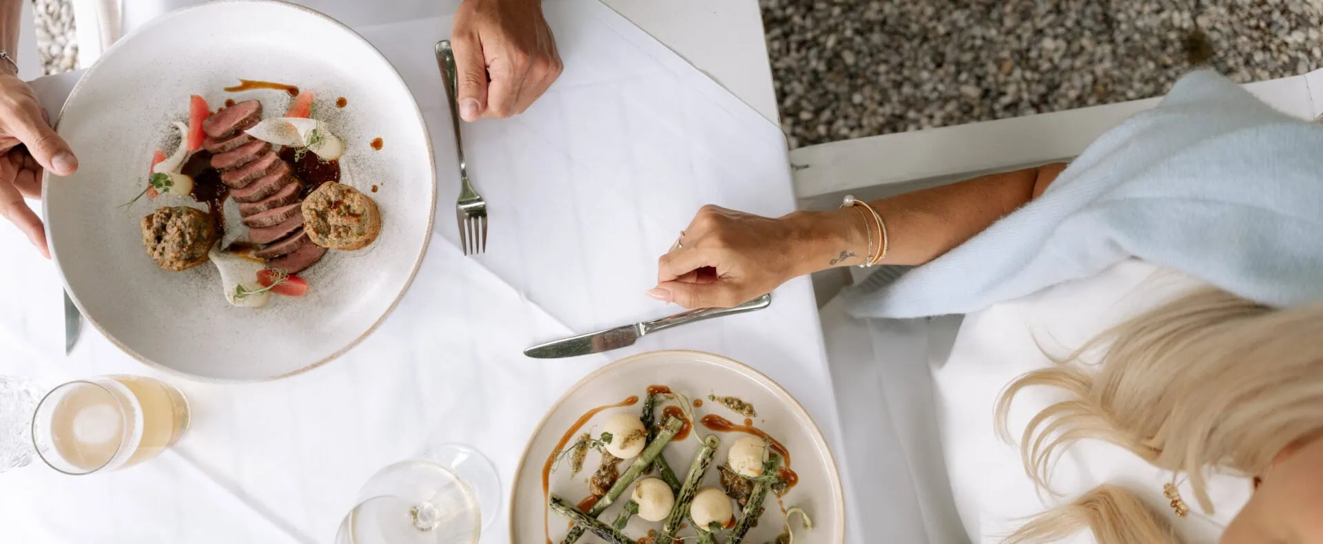 Fein angerichtete Speisen auf weiß gedecktem Tisch im Restaurant Schlosswirt zu Anif.
