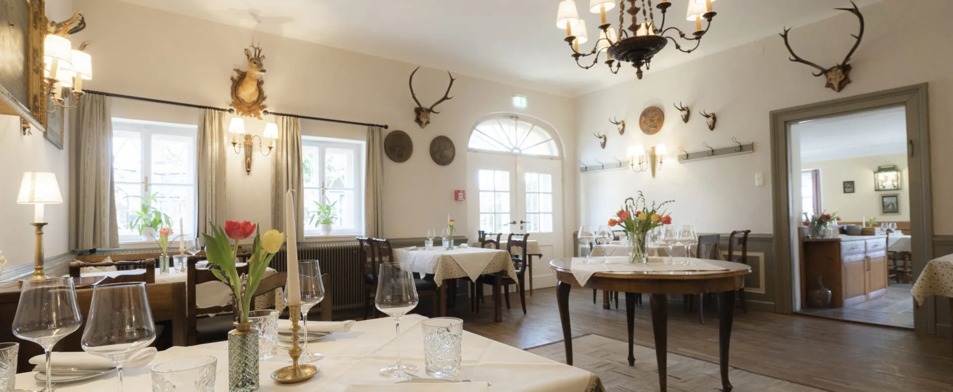 Elegant gedecktes Restaurant im Schlosswirt zu Anif mit historischem Ambiente und weißen Tischen.