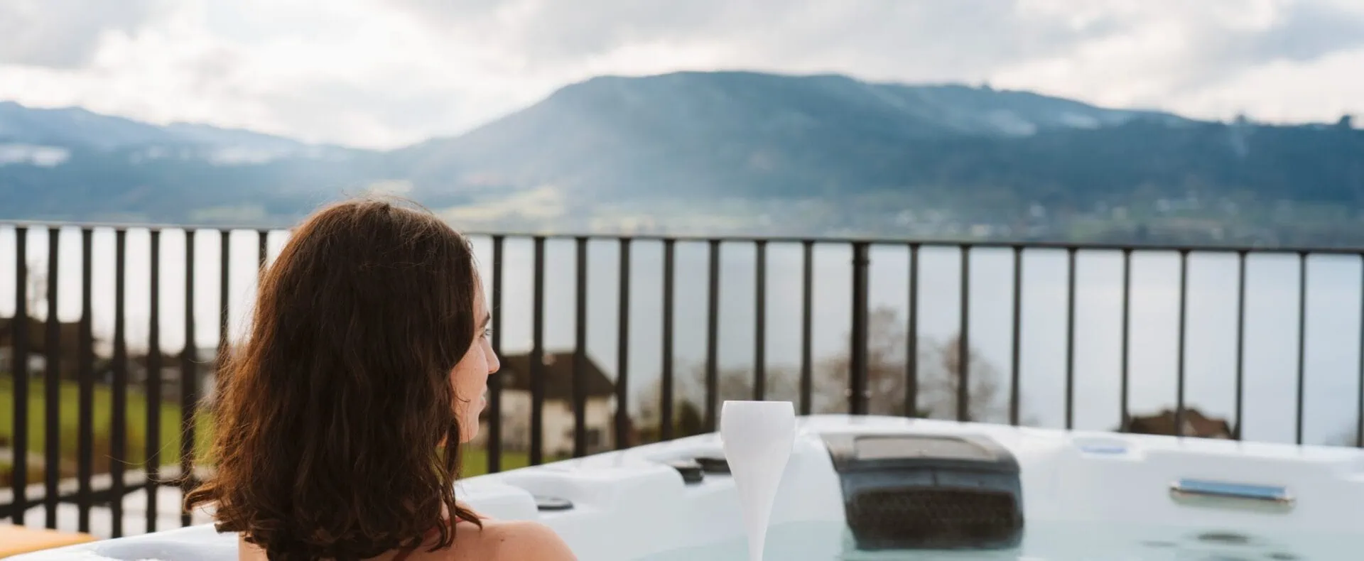 Privater Outdoor-Whirlpool der ORANGE LOUNGE in Weyregg mit Blick auf den Attersee und die umliegenden Berge.